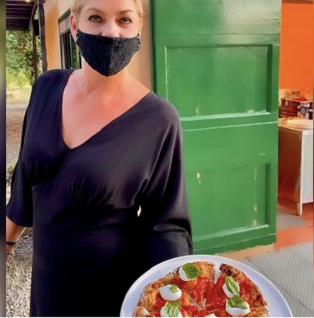 this photo shows a staff member with a photo of a pizza from Sting's new pizzeria in Tuscany, Italy